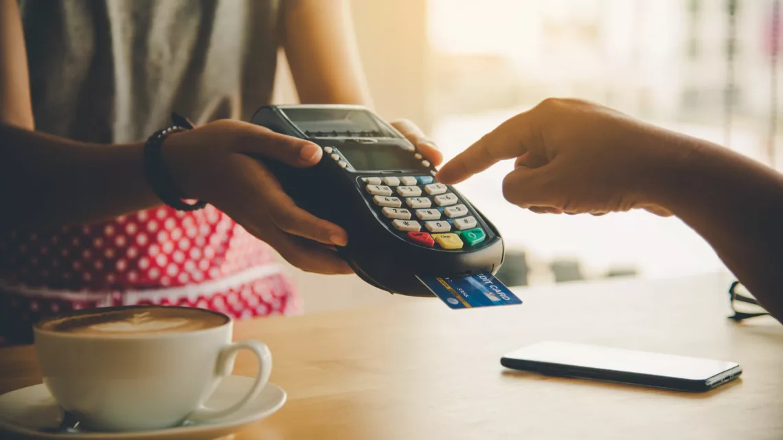 A photo of a customer making a selection on a credit card machine at a coffee shop