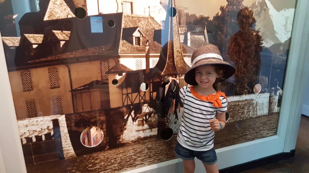 girl posing in costume next to historic photo of Oberhofen Castle in Switzerland