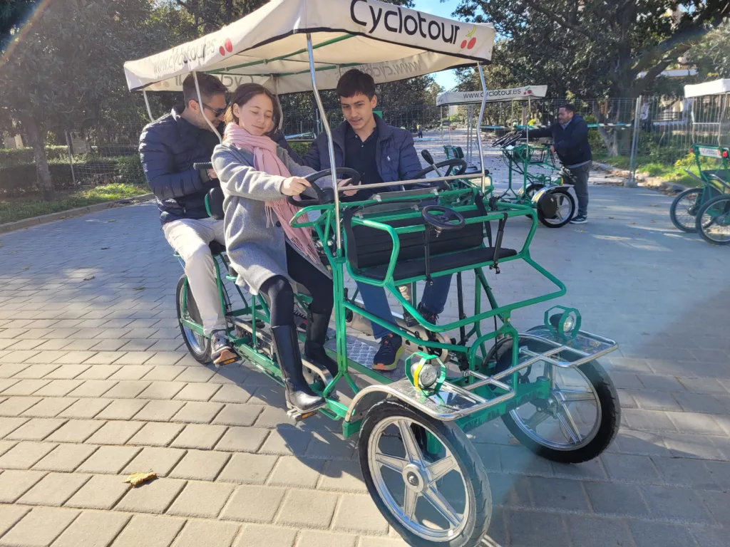 Family riding in a 4-seater 4 wheel bike in Maria Luisa Park in Seville