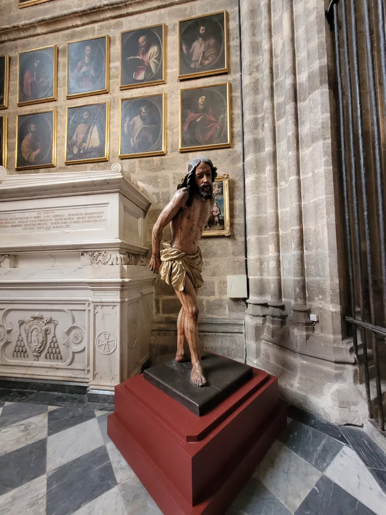 Photo of a statue of a man hunched and walking inside the Seville Cathedral