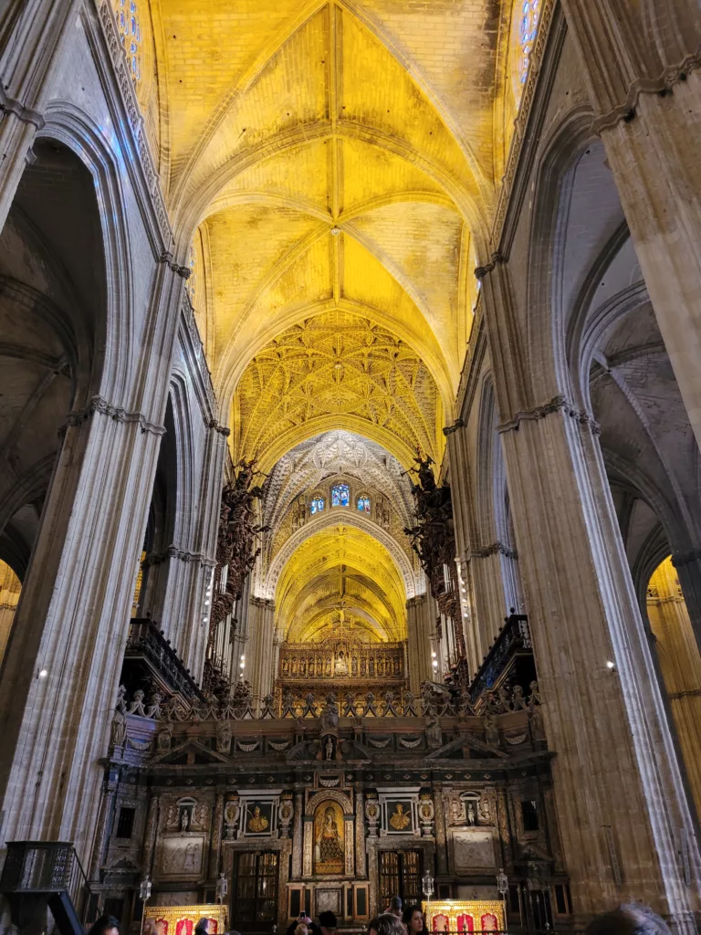 A photo of the ceiling inside the Seville Cathedral showing the natural light illuminating it in a yellow hue